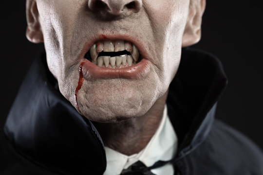 Close-up of dracula with black cape showing his scary teeth. Vam