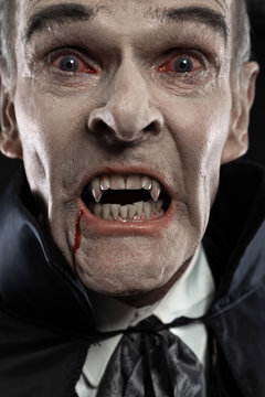 Dracula with black cape showing his scary teeth. Vamp fangs. Stu