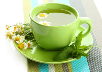 Cup of herbal tea with wild camomiles and mint, isolated