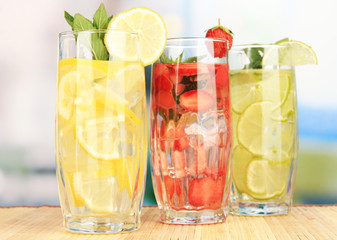 Glasses of fruit drinks with ice cubes on table in cafe