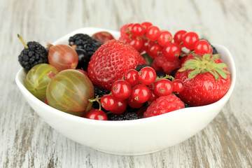 Ripe berries in bowl on table close-up