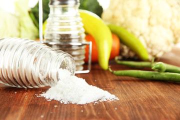Composition of salt and pepper mills and fresh vegetables,