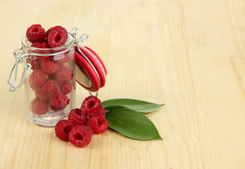 Ripe raspberries in bank on wooden table close-up