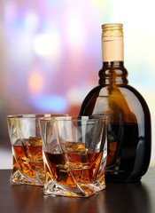 Glass of liquor with bottle, on dark background