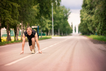 Sportive man in starting position prepared to run