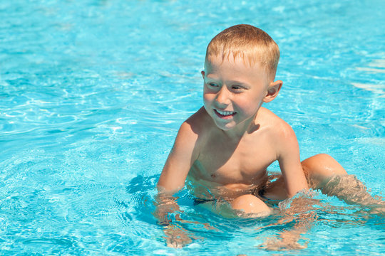 Charming smiling boy sitting into the pool