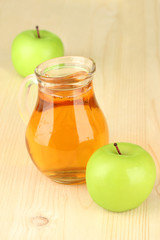 Full jug of apple juice and apple on wooden background