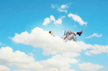 Businessman lying on clouds