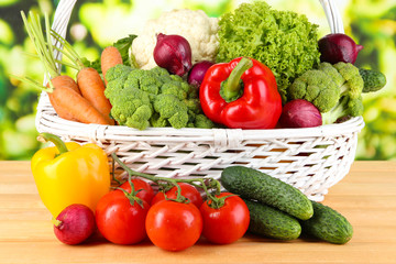 Fresh vegetables in white wicker basket on bright background
