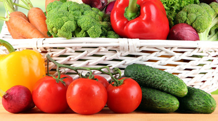 Fresh vegetables in white wicker basket on bright background