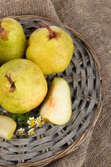 Pears on braided tray on burlap  on wooden table