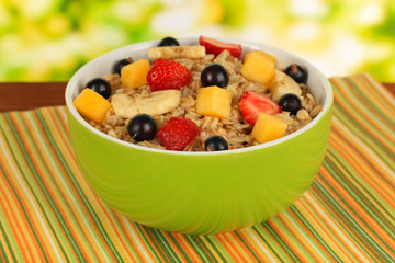 Oatmeal with fruits on table on bright background