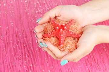 Beautiful woman's hands holding handful of sea salt,