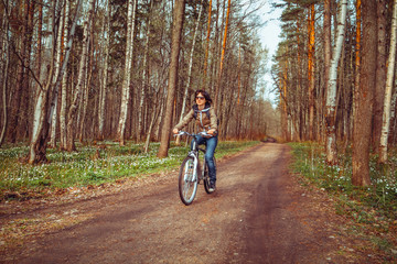 Fototapeta premium Young woman riding bicycle on a forest