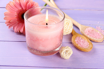 Beautiful pink candle with flower on purple wooden background