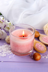 Fototapeta na wymiar Beautiful pink candle with flowers on purple wooden background