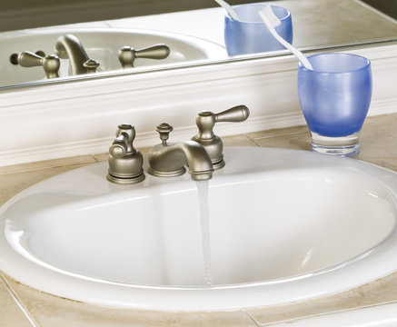 White Bathroom Sink and Faucet in Open Position with Clean Water