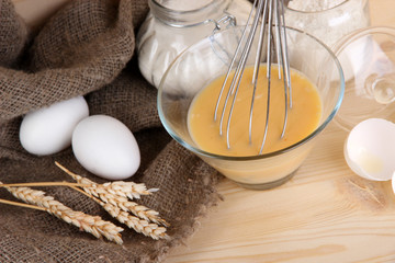 Ingredients for dough on wooden table on wooden background