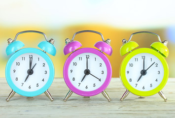 Colorful alarm clocks on table on bright background