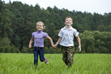 Naklejka na ściany i meble Children running on the green grass in the park