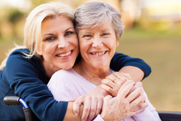 middle aged woman embracing disabled senior mother - Powered by Adobe