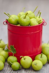Green pears in the red basket on the wooden background