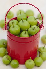 Green pears in the red basket on the wooden background