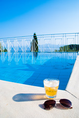 Beer and sunglasses by swimming pool