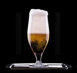 Frosty glass of light beer on black background