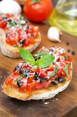 Italian bruschetta with tomato, olives, basil and cheese closeup