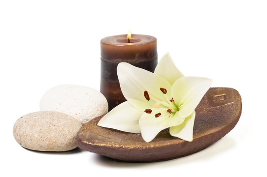spa decoration with stones, candle and lily on a wooden plate