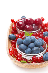 fresh blueberries, cherries and red currants in a wooden bowl