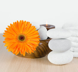 Spa decoration with candle, orange Gerbera daisy and spa stones