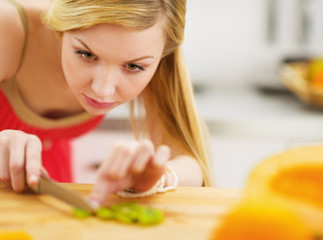 Obraz na płótnie Canvas Young woman cutting salad in kitchen