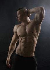 Fototapeta na wymiar Young sexy man with athletic body posing on black background.