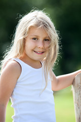 Pretty little girl in white singlet smiling outdoors in summer