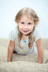 Fototapeta premium Playful Caucasian girl sitting on sofa pillows