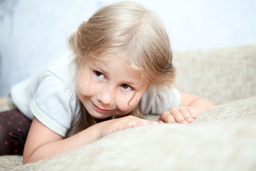 Obraz na płótnie Canvas Playful Caucasian girl hiding her face in sofa pillows