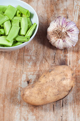 Green beans, potato and garlic, on a wooden table
