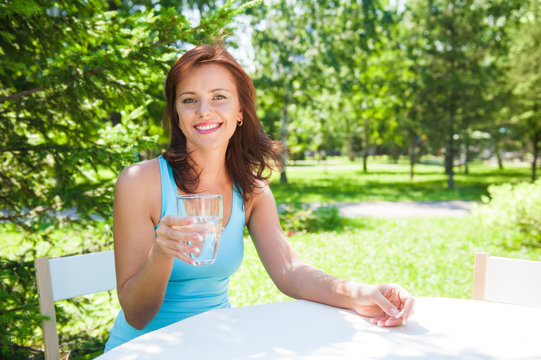 Portrait of young beautiful woman drinking water on picnic