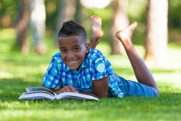 Outdoor portrait of student black boy reading a book - African p