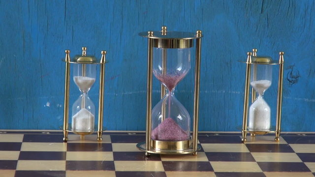 three sandglass on chessboard. Time concept