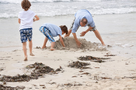 alleinerziehender vater mit söhnen kindern spielen am strand