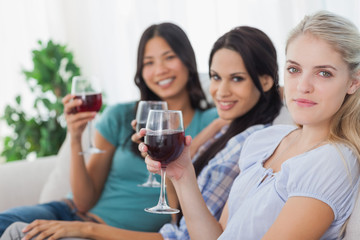 Cheerful friends having red wine together looking at camera