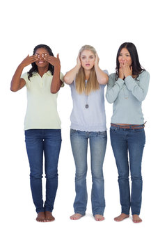 Young women acting out three wise monkeys