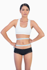 Obraz premium Self confident slim woman measuring her waist