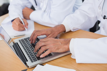 Close up on doctors hands typing on laptop