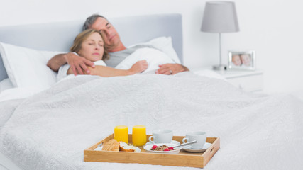 Obraz na płótnie Canvas Couple sleeping with breakfast tray on bed