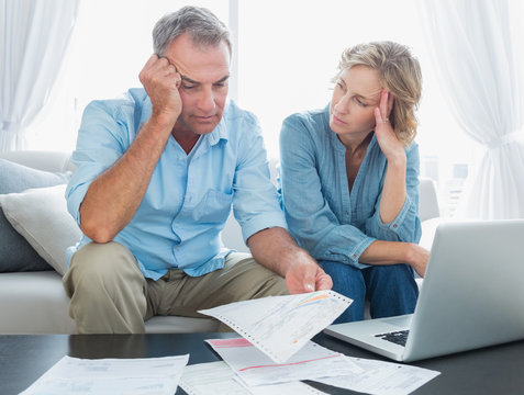 Worried couple using their laptop to pay their bills