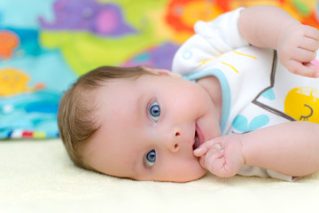 2 months old infant baby girl sucking thumb while lying on bed © Denniro